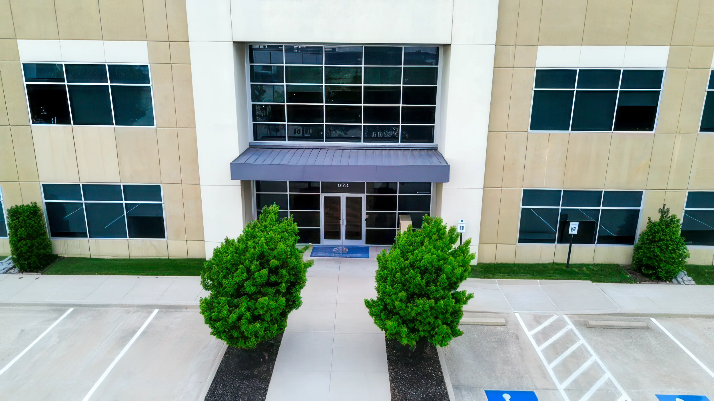 Stone and glass main entrance of 8454 Parkwood, framed by manicured landscaping